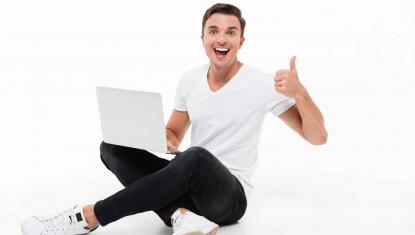 młody mężczyzna zadowolony trzyma w ręku laptop
