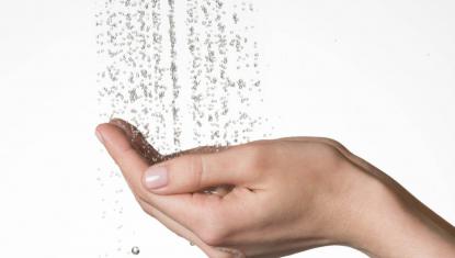 Dłoń młodej osoby chwyta wodę płynącą z baterii prysznicowej