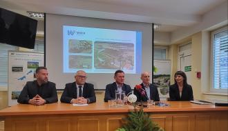 Pięcioro biznesowo ubranych osób, czterech mężczyzn, zasiada za stołem prezydialnym, w tle prezentacja na ekranie 